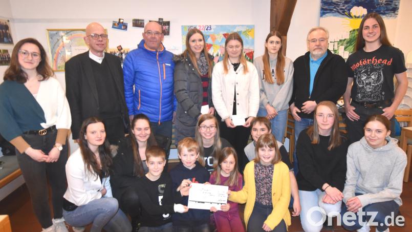 Bei der Spendenübergabe im evangelischen Gemeindehaus : Pfarrer Thomas Schertel (Zweiter von links), Thomas Dirler (Dritter von links), Anna Baldauf (Vierter von links), Lea Bleisteiner (Fünfte von links) und Wolfgang Stowasser (Zweiter von rechts); des Weiteren die Betreuer der Jungschargruppe und Kinder bei der Gruppenstunde. Bild: no