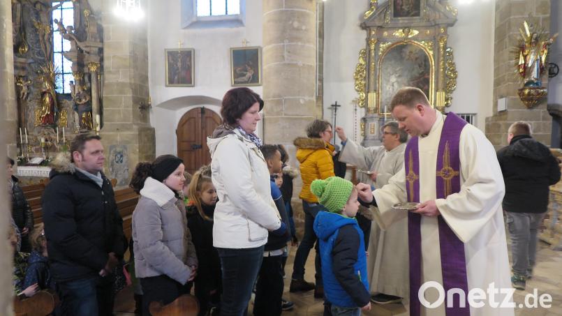 Stadtpfarrer Thomas Kraus und Gemeindereferent Jochen Gößl (von rechts) zeichneten das Aschenkreuz auf die Stirn der Kinder und ihrer Eltern. Bild: jzk