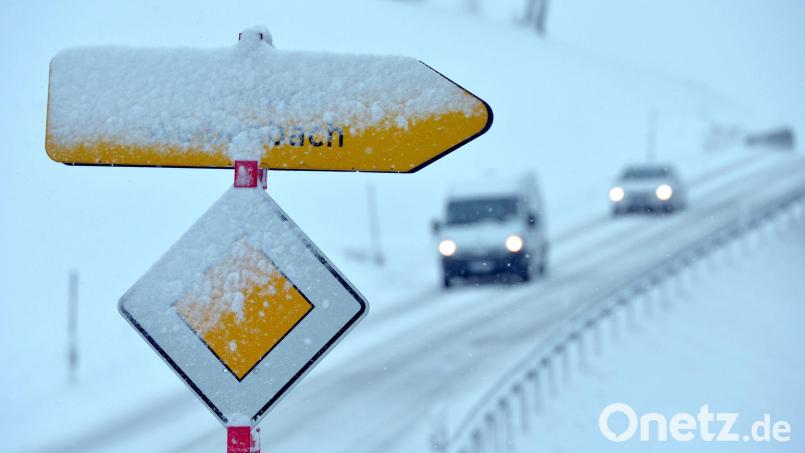 Neuschnee bedeckt ein Vorfahrtsschild und einen Wegweiser. Bild: Uwe Lein/dpa/Symbolbild
