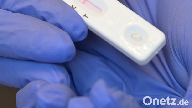 Eine Person hält während eines Corona-Tests den Plastikstreifen mit dem negativen Testergebnis in der Hand. Symbolbild: Soeren Stache/dpa