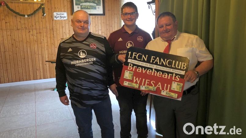 Als Beitrag zur Finanzierung des Ersatzfahrzeugs des BRK-Betreuungsdienstes übergaben Josef und Raphael Bayer (von links) eine 500-Euro-Spende des 1. FCN-Fanclubs „Bravehearts“ an BRK-Bereitschaftsleiter Robert Wolfrum. Bild: wro