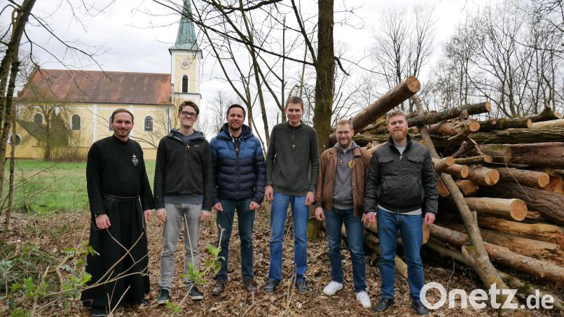 Pater Dominikus (links) mit fünf jungen Männern, die in den Orden eintreten wollen, vor dem ersten Holz aus dem Klosterwald, das zur Heizung in der geplanten Hackschnitzel-Anlage vorgesehen ist. Im Hintergrund die Wallfahrtskirche des Klosters.k. Bild: Passionisten Schwarzenfeld/exb