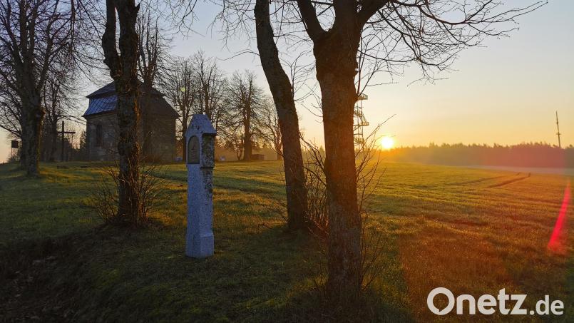 Am Horizont lugt die Morgensonne hervor; links verborgen hinter dem Baum der Aussichtsturm und daneben die Kalvarienbergkapelle. Bild: hzi