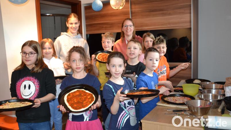 Stolz zeigen die Mädchen und Buben ihre leckere Pizza mit selbst gesammelten Kräutern, die anschließend in den Ofen kam. Bild: gi