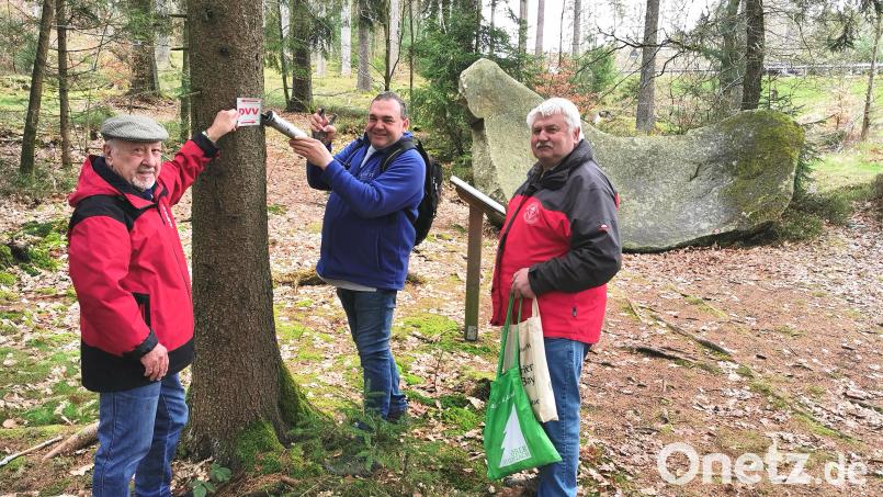 Die Stadt Oberviechtach und der Wanderverein mit Vorsitzenden Alois Früchtl (von rechts), Streckenwart Bernhard Gäbl und Wanderwart Toni Zimmet markieren den „Kapellen- und Goldsteig-Naturwanderweg“ mit dem Schild „DVV“ neu. Im Hintergrund das steinerne Naturdenkmal „Sattelroß“. Bild: Portner