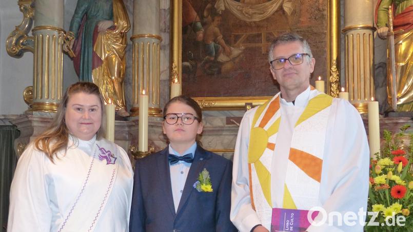 Diakonin Vivian Bayer-Trentini, Konfirmand Benno Klemm und Pfarrer Marcio Trentini vor dem Hochaltar in der evangelischen Pfarrkirche Kohlberg. Bild: hme