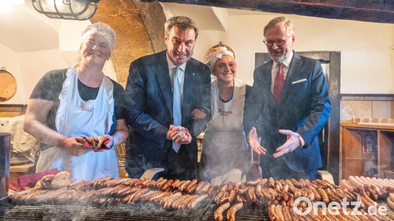 Beim Besuch in der historischen Regensburger Wurstkuchl schauten der tschechische Ministerpräsident Petr Fiala (rechts) und der bayerische Ministerpräsident Markus Söder (Zweiter von links) beim Grillen der Bratwürste zu. Bild: Armin Weigel/dpa