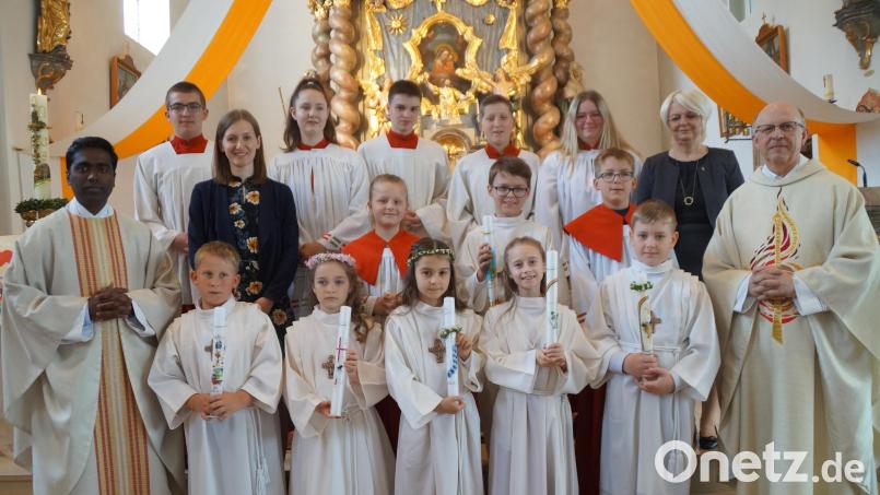 Pfarrer Herbert Rösl (rechts) und Pater Savari (links) freuen sich zusammen mit der Mesnerin und den Ministranten mit den Kommunionkindern: (von rechts) Anton Heinrich, Nele Bronold, Nele Gradwohl, Jana Bauer und Toni Landgraf sowie (mittlere Reihe Zweiter von rechts) Anton Kiesl. Klassleiterin Rebecca Lorenz (Dritte von links) begleitete ihre Schüler. Bild: wel