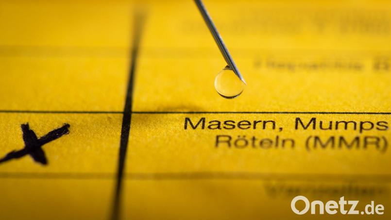 Eine Spritze liegt auf einem Impfpass in Vorbereitung auf eine Schutzimpfung gegen Masern. Seit 2020 ist die Impfung Pflicht. Eine Ärzteehepaar soll falsche Atteste zur Befreiung ausgestellt haben und muss sich deshalb in Schwandorf vor Gericht verantworten. Bild: Friso Gentsch/dpa/Illustration