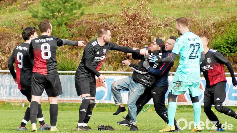 Spieler und Ordner halten den jungen Mann fest, der den Platz gestürmt hatte. Bild: Rainer Rosenau