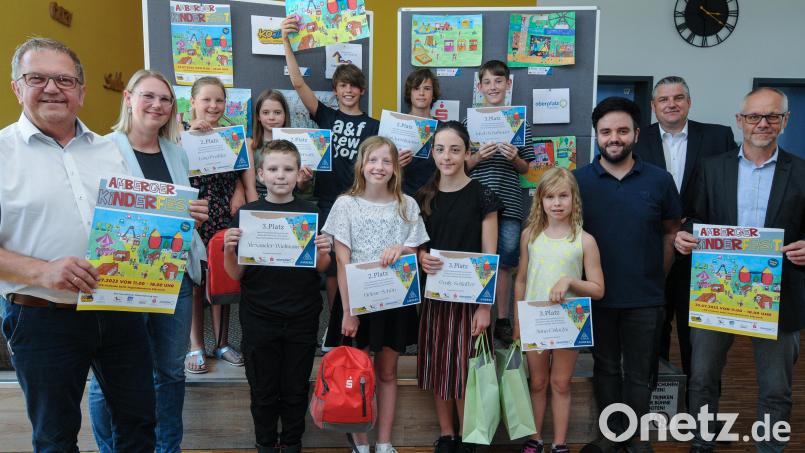 Sven Taschek (hinten, Mitte, mit dem Bild in der Luft) hat den Malwettbewerb zum Amberger Kinderfest gewonnen. Es gratulierten unter anderem Bürgermeister Martin Preuß (links) und Jugendamtsleiter Thomas Boss (rechts). Bild: Stephan Huber