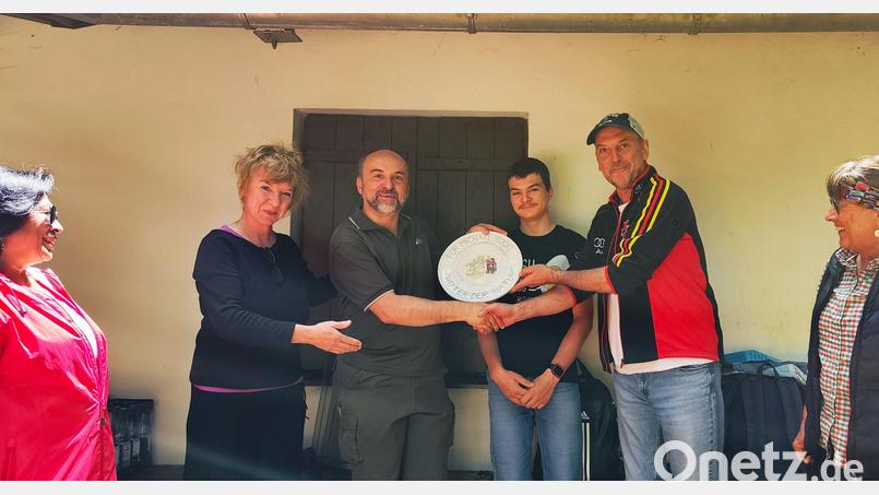 Eine Porzellanscheibe überreichte Dritter Vorsitzender Jürgen Heinl (Zweiter von rechts) stellvertretend für den Verein Badehaus Maiersreuth an Michael Rückl (Dritter von links). Links daneben Vorsitzende Susanne Neumann, außerdem im Bild Teilnehmende der Wanderung. Bild: Jürgen Heinl/exb