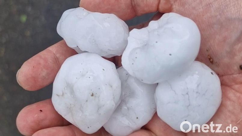 Große Hagelkörner liegen nach einem Unwetter auf einer Hand. Bild: Hutter/vifogra/dpa