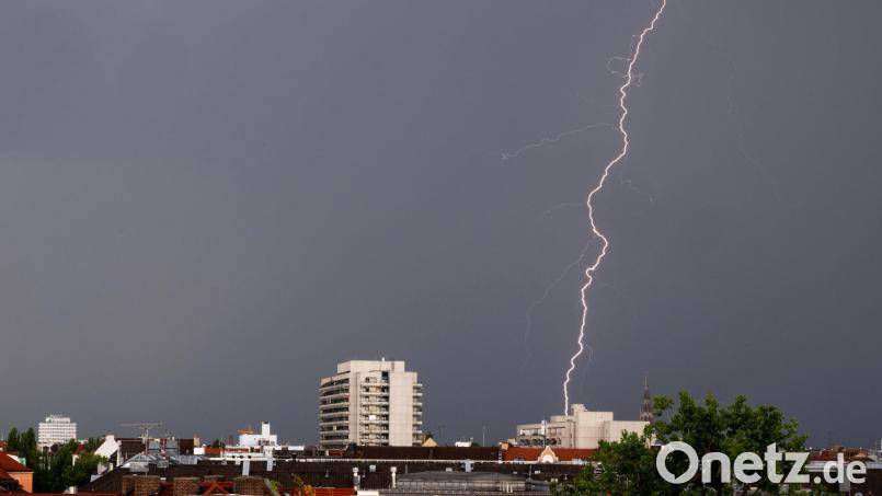 Ein Gewitter mit Blitzen zieht in den Abendstunden über die Dächer von München. Bild: Peter Kneffel/dpa