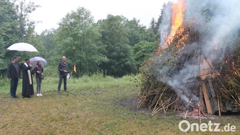 Pfarrer John Subash Vincent segnet das von Kommandant Andreas Götz (rechts) entfachte Johannisfeuer. Bild: pi