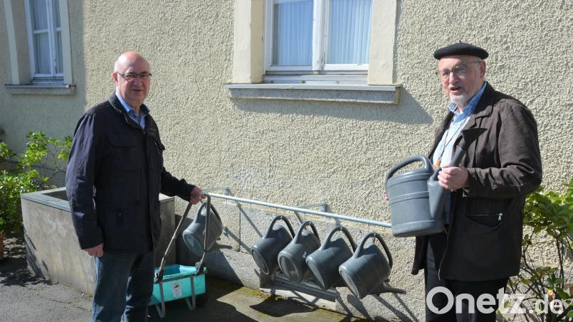 Kirchenpfleger Wolfgang Hecht (links) und Stadtpfarrer Anton Witt stellten das neue Pfandsystem für die Gießkannen und Transportwagen am Mitterteicher Friedhof vor. Wer zwei Euro einwirft, kann sich eine Gießkanne ausleihen, beim Zurückbringen erhält er das Geld zurück. Bild: jr
