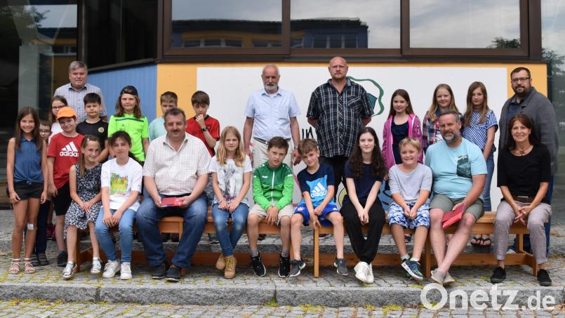 Sieben Bänke werten in der Grundschule die Pausenbereiche im Freien auf. Rektor Troidl, die Sponsoren und die Kinder der vierten Klasse nutzten die Gelegenheit für ein Probesitzen. Bild: Stadt Schönsee/exb