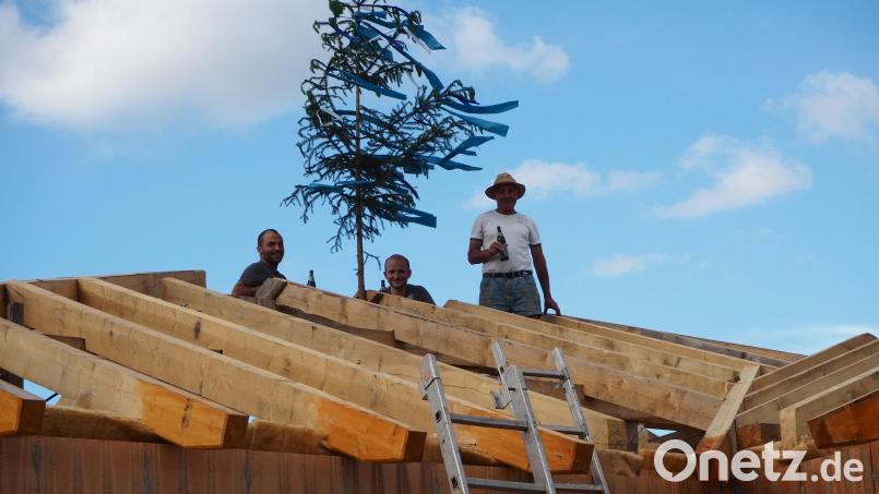 Eine wichtige Etappe ist geschafft, der Rohbau steht. Beim Hebfest stößt Hans Lang mit seinen beiden Söhnen an. Bild: Sabine Fehn /exb