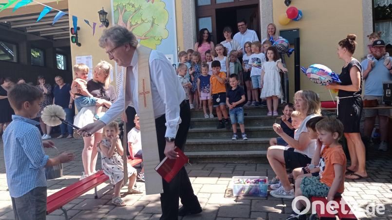 Mit dem Lied „Wir feiern heut’ ein Fest“ eröffneten die „Piccolino“-Kinder die Jubiläumsfeier. Mit im Bild Stadtpfarrer Bernd Philipp, der den Garten und das Festgelände segnete. Auf der Treppe hinter den Kindern (von links) Bürgermeisterin Margit Bayer, Elternbeiratsvorsitzende Bianca Bayer, BRK-Geschäftsführer Holger Schedl und Kinderhausleiterin Alice Hübsch. Bild: fpoz