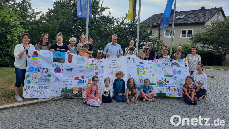Das Bücherei-Team übergibt Bürgermeister Thomas Meiler (Mitte) zusammen mit kleinen und großen Lesern und der Kindergartenleitung das Banner zum 1075. Geburtstag der Gemeinde. Bild: Gemeindebücherei/exb
