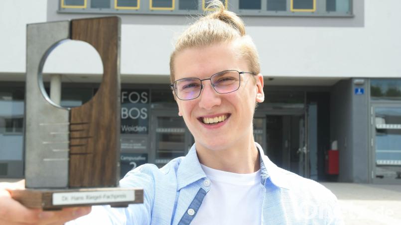 Simon Völkl mit seinem Dr.-Hans-Riegel-Fachpreis vor dem Gebäude der FOSBOS Weiden Bild: Gabi Schönberger