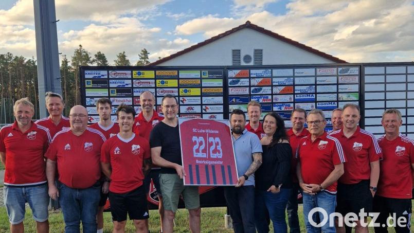 Der SC Luhe-Wildenau überreicht das Trikot mit den Unterschriften der Meisterspieler 2022/23 an Familie Spitzer, die es ersteigert hat. Die 1000 Euro aus der Versteigerung gehen als Spende an die Palliativstation am Klinikum Weiden. Bild: Armin Goschler/exb