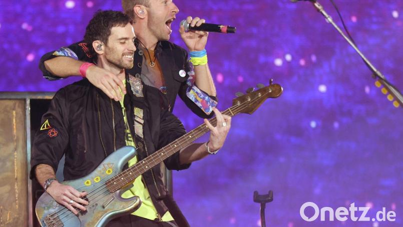 Chris Martin (oben), Sänger von Coldplay umarmt Guy Berryman, den Bassisten der Band, während der "Music of the Spheres"-Tour auf der Bühne. Bild: Suzan Moore/PA Wire/dpa/Archivbild