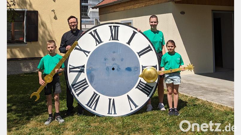 Pfarrer Johannes Arweck und Oberministrantin Theresa Popp mit den jüngsten Minis Tim und Isabella vor dem großen Ziffernblatt der Ursensollner Kirchturmuhr Bild: Manuela Popp/exb