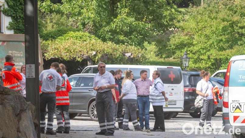 Diverse Helfer stehen in der Einfahrt eines Unternehmens. Bild: Peter Kneffel/dpa