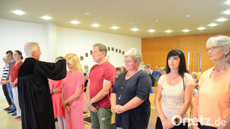 Pfarrer Dominic Naujoks segnet die Ehrenamtlichen. Bild: Kunz