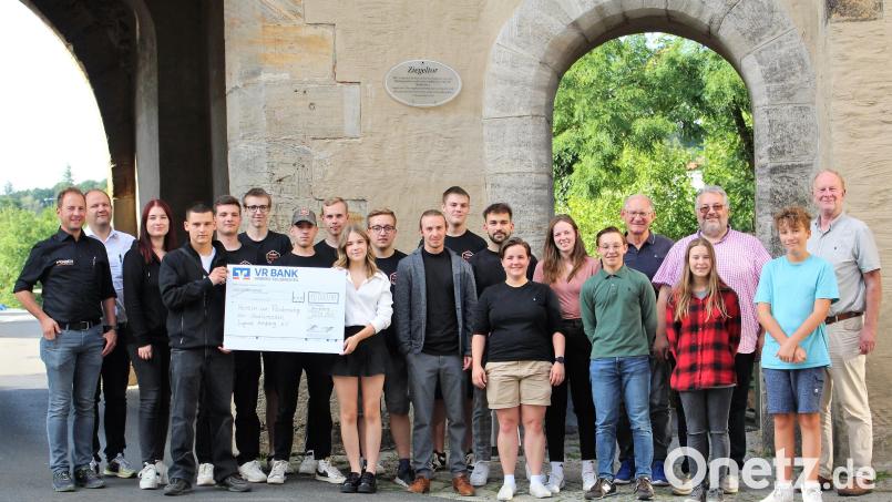 Alexander Färber, Benjamin Färber und ihre Auszubildenden, das &quot;Juniorteam&quot; (rechts) übergeben 10.000 Euro an die Schweppermann-Stadtgruppe der KSJ Amberg und ihre Vorstände. Geplant für die Jubiläumsfeier ist auch eine Führung durch Innenleben des Ziegeltors, dem Hauptsitz ihres Treffpunktes. Bild: Dagmar Williamson