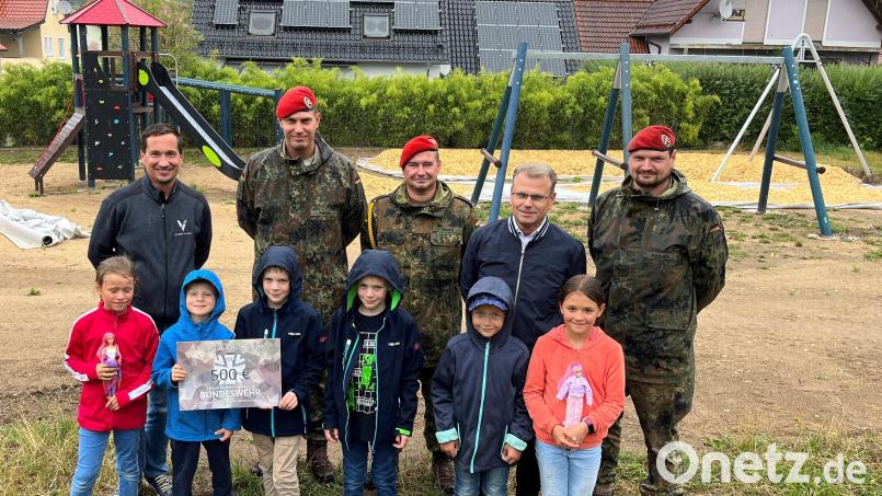Spielplatzinitiator Christian Trummer (hinten links) und die Kinder freuen sich zusammen mit Bürgermeister Karlheinz Budnik (hinten, Zweiter von rechts) über die Spende der Soldaten mit Hauptmann Christian Knorn (hinten, Zweiter von links). Bild: Stadt Windischeschenbach/exb