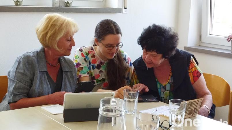 Eine ehrenamtliche Helferin (Mitte) erklärt zwei Teilnehmern den Umgang mit Handy und Tablet. Bild: Kathleen Busse, Malteser/exb