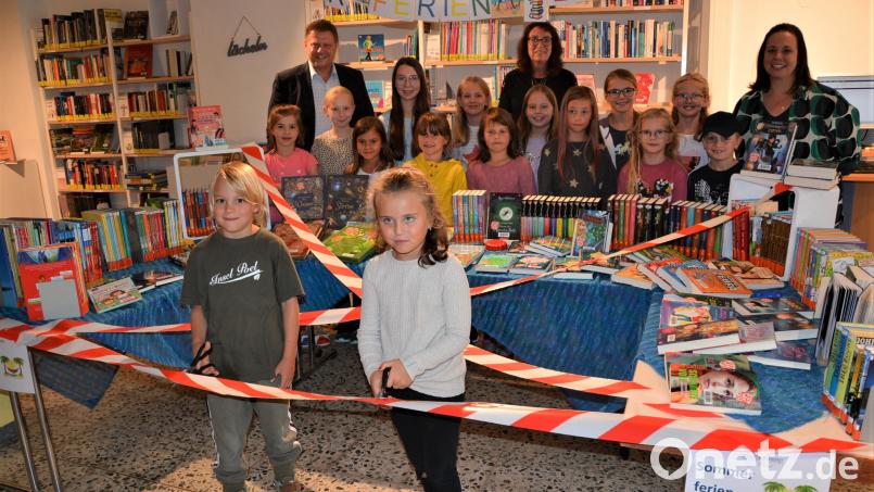 Leonhard und Paula (im Vordergrund) eröffnen den diesjährigen Sommerferien-Leseclub in der Stadtbücherei Mitterteich, indem sie mit ihrer Schere das Eröffnungsband durchtrennen. Bild: jr