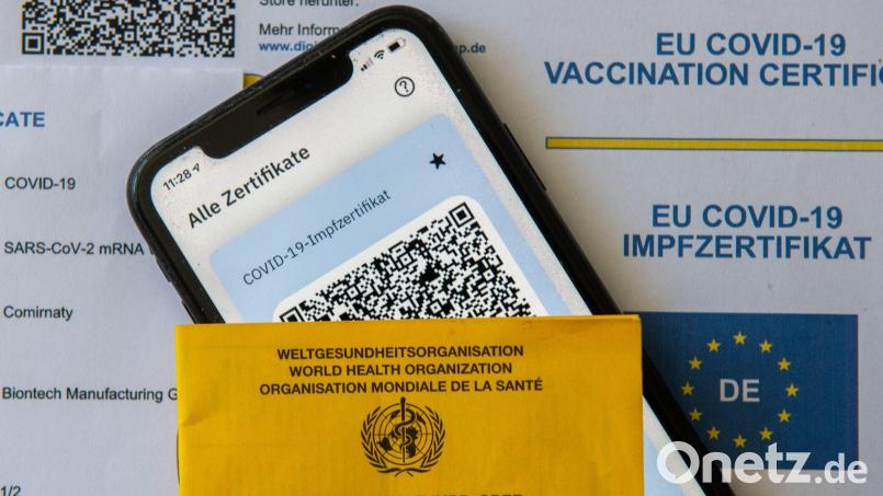 Ein Impfpass und ein Smartphone mit der CovPass-App liegen auf einem Impfzertifikat. Wer einen gültigen Impfpass hatte, konnte sich während der Pandemie in Apotheken ein digitales Zertifikat holen. Ein Paar versuchte das mit einer Fälschung. Bild: Stefan Puchner/dpa/Symbolbild