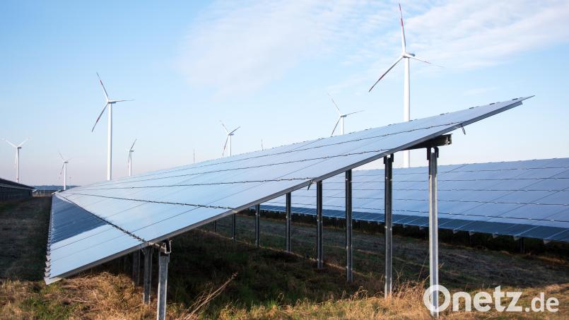 Blick auf einen Solarpark, im Hintergrund sind Windräder zu sehen. Bild: Daniel Bockwoldt/dpa