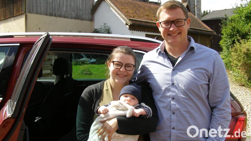 Julia Schneider mit dem kleinen Leo auf dem Arm sowie Papa Martin Schneider vor Opas VW-Tiguan, in dem am 22. Mai das zweite Kind der jungen Familie zur Welt kam. Bild: pz