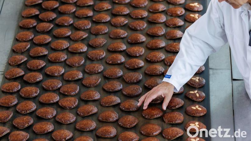 Frisch gebackene Lebkuchen laufen auf einem Band aus einem Ofen. Bild: Daniel Karmann/dpa