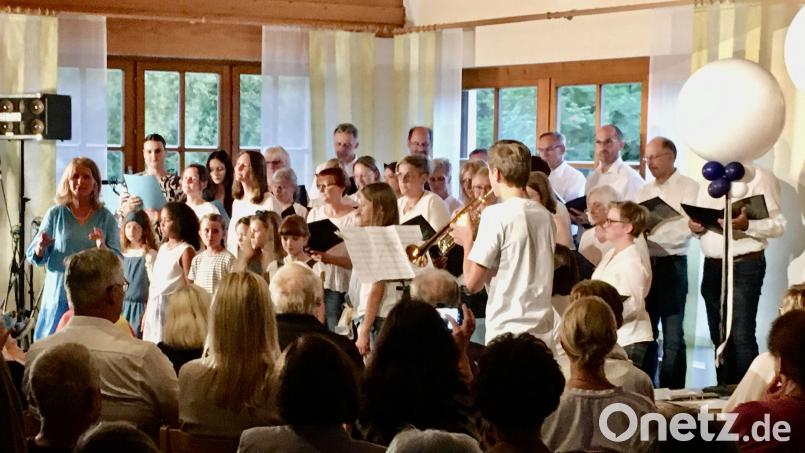 Als Gemeinschaftschor singen die beiden Chöre Happy Voices (Hintergrund) und Herzwärts (Vordergrund) zwei Zugaben. Die Chorleiterin von Herzwärts, Gertrud Siegert (links) moderiert den Abend, die Chorleiterin von Happy Voices, Andrea Eichenseer (ganz rechts, mittlere Reihe), hat sich in den Chor eingereiht. Bild: Michael Luber/exb