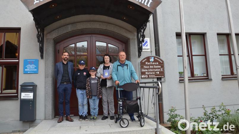 Bürgermeister Armin Bulenda (links) dankt Eleonore und Manfred Zirkel für den 25. Aufenthalt in Moosbach. Er überreicht ihnen eine Chronik des Marktes Moosbach. Mit dabei ihre beiden Enkel. Bild: gi