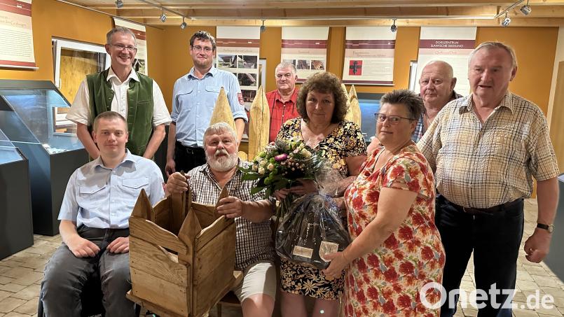 Bürgermeister Franz Grabinger (hinten links) gratuliert im Dokuzentrum bei Weiding dem Ortsheimatpfleger Heinrich Schwarz (sitzend mit der Brunnennachbildung) zusammen mit Vertretern der Vereine zum 70. Geburtstag. Für Ehefrau Monika gibt es einen Blumenstrauß. Bild: Thomas Fritsch/exb
