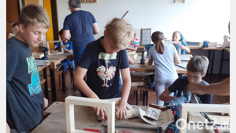 Die Buben und Mädchen sind mit großem Eifer bei der Sache und bauen aus den Einzelteilen Vogelfutterhäuschen. Bild: Josef Söllner/exb