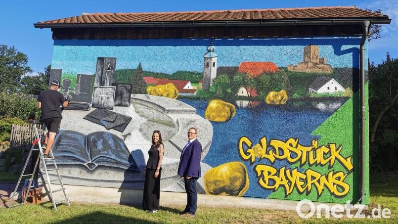 Zweiter Bürgermeister Egbert Völkl und Margit Boch vom Stadtmarketing freuen sich über die künstlerische Gestaltung der Trafostation am Marktweiher durch den Graffiti-Sprayer Markus Raab. Das Wandbild ist 3,60 mal 7,50 Meter groß. Bild: Portner