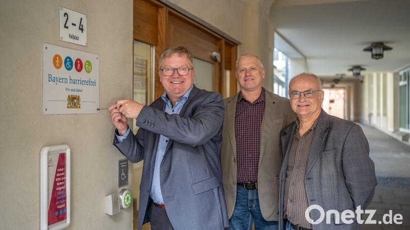 Oberbürgermeister Michael Cerny schraubt das Signet "Bayern barrierefrei" fest. Josef Singer (Leiter Zentrale Dienste/rechts) und Martin Kroher (Schwerbehindertenvertretung/Mitte) freuen sich ebenfalls über die Auszeichnung. Bild: Michael Golinski, Stadt Amberg/exb