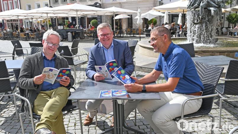 Kulturreferent Fabian Kern (von links), Ambergs Oberbürgermeister Michael Cerny und VHS-Leiter Reiner Volkert blättern im neuen Volkshochschulprogramm. Bild: Susanne Schwab, Stadt Amberg/exb