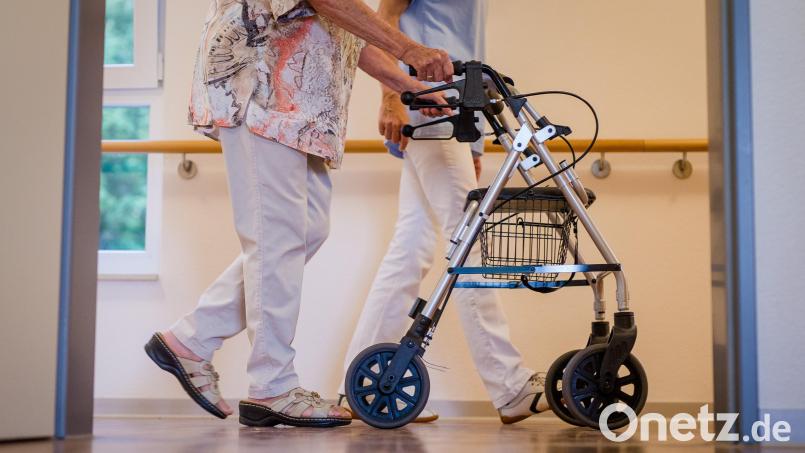 Eine Pflegekraft begleitet eine Seniorin mit dem Rollator. Wie wollen Politiker den Spagat zwischen fairem Lohn und steigenden Heimkosten schaffen? Symbolbild: Christoph Schmidt/dpa