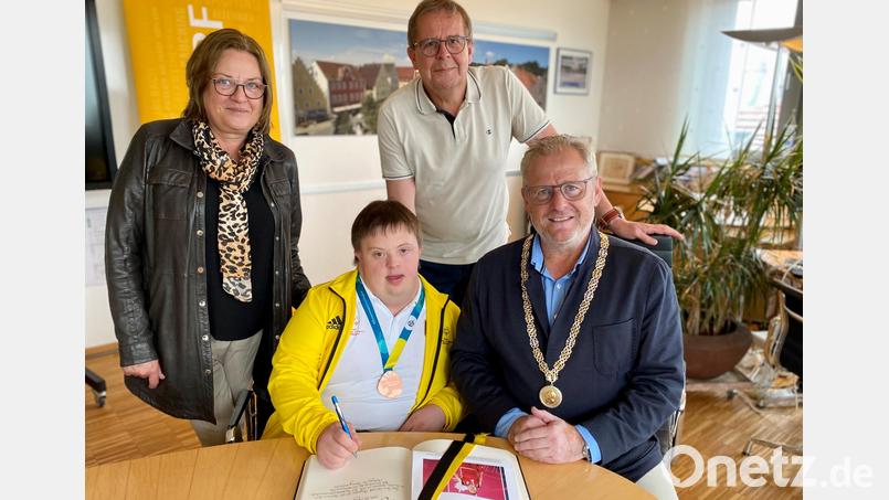 Alexander Harrieder trägt sich im Beisein seiner Eltern Brigitte und Peter Harrieder in das Goldene Buch der Stadt Schwandorf ein. Oberbürgermeister Andreas Feller gratuliert zum Team-Erfolg bei Special Olympics. Bild: Stadt Schwandorf/exb