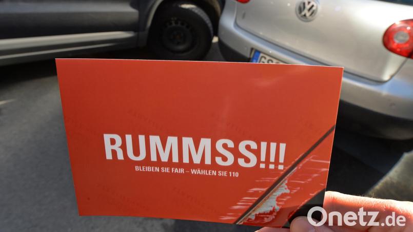 «Rummss!!!» steht auf dieser Postkarte, die vor eine gestellte Unfallsituation gehalten wird. Die Aktion in Niedersachsen erinnerte Fahrer daran, im Falle eines kleinen Unfalls „fair“ zu bleiben und die Polizei zu informieren. Symbolbild: Holger Hollemann/dpa