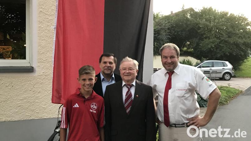 Erinnerungsfoto vor der rot-schwarzen Fahne: Club-Jugendspieler Lukas Kellner, Zweiter Bürgermeister Günther Koller, der für 25 Jahre Mitgliedschaft geehrte Altbürgermeister Gerd Geismann und Präsident Mike Schulz. Bild: FCN-Fanclub Zur Linde Kleinfalz/exb
