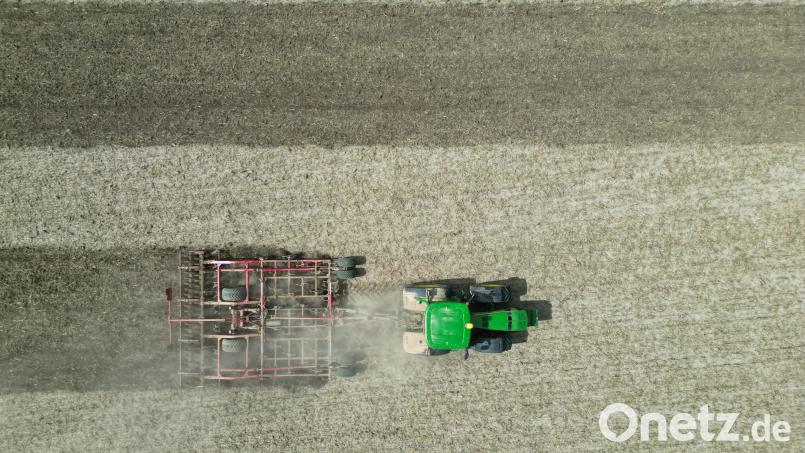 Ein Traktor lockert mit einer Egge den Boden auf einem Feld auf und wirbelt dabei eine Staubwolke auf. Bild: Matthias Bein/dpa